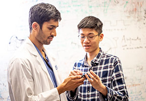Dr. Sharat Raju, left, a surgical resident in otolaryngology-head and neck surgery, discusses the app with Justin Chan, a doctoral student in the Allen School.