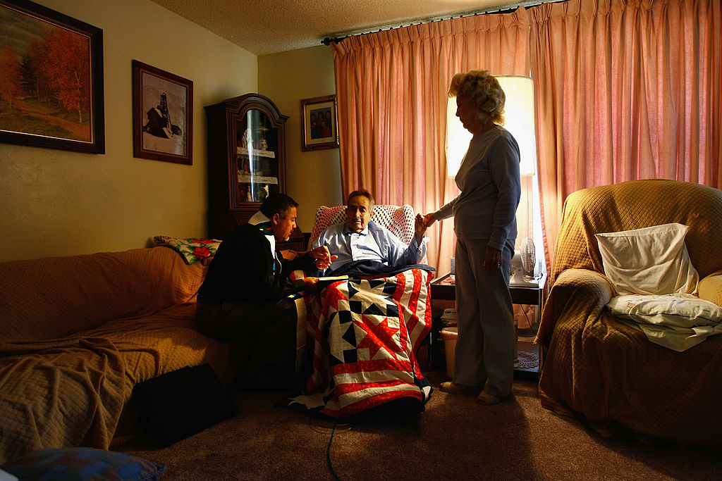 A hospice chaplain prays with an ill patient and his loved one in their home.