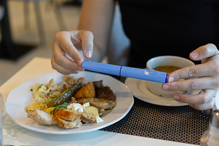 picture of woman holding semaglutide injection pen during meal time