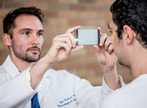 picture of a physician using a smartphone to take a picture of a man