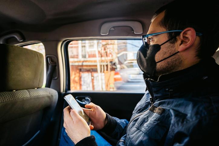 picture of man wearing a mask in the back of a rideshare auto