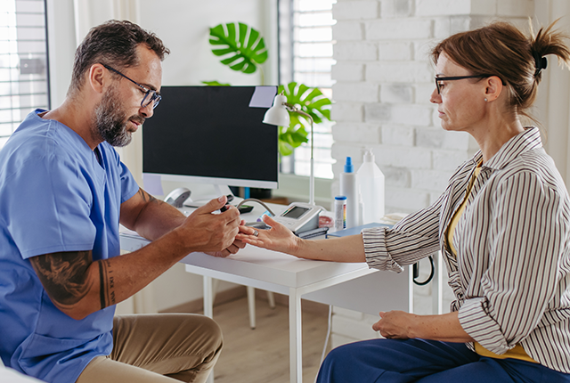 picture of doctor collecting blood sample from woman's fingertip for glucose testing