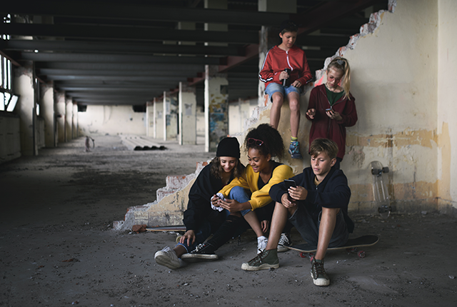 picture of teens looking at smartphones in abandoned building