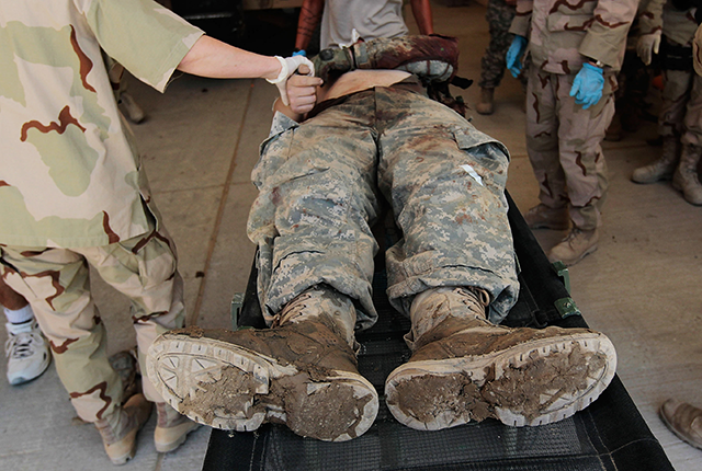 picture of a U.S. soldier just wounded in a battlefield explosion is surrounded by medics on June 18, 2010 at Kandahar Air Field, Afghanistan
