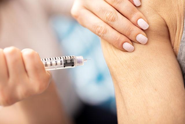 A woman receives an insulin shot in the arm.