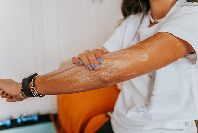 picture of adult woman applying sunscreen to her arm