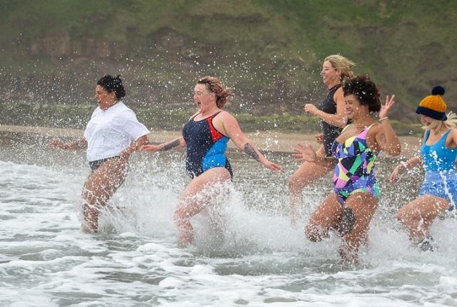 women running into cold water new years day
