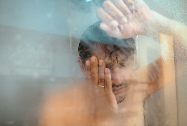 picture of a man looking weary while taking a shower
