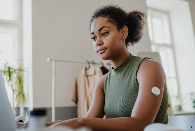 Woman with a glucose monitor looking at computer screen