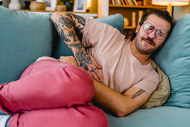 man on sofa experiencing stomach pain