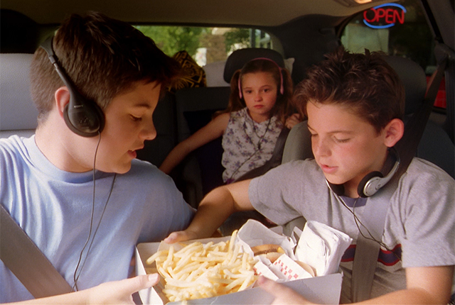 picture of children in a car holding several orders of French fries