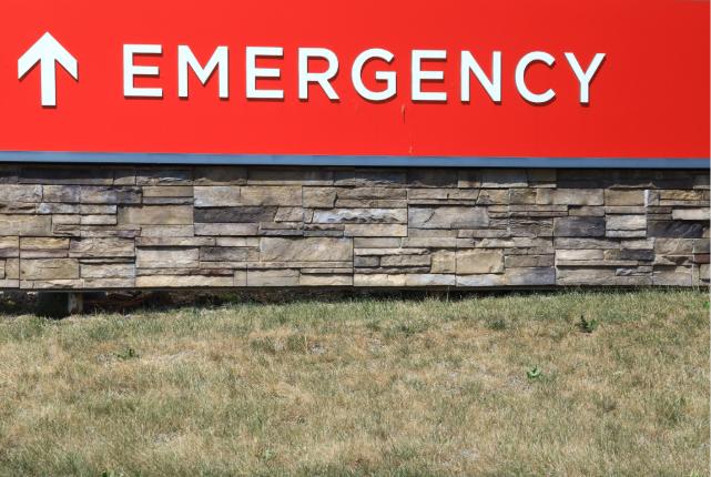 Exterior sign pointing to a hospital emergency department entrance.