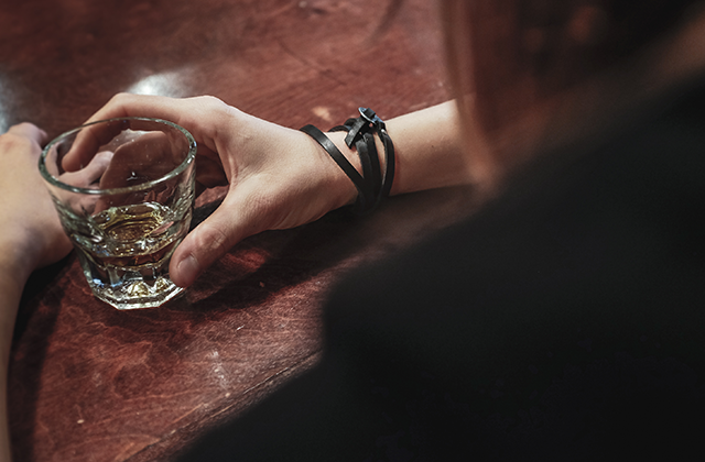 picture of a person holding a glass of alcohol at a bar