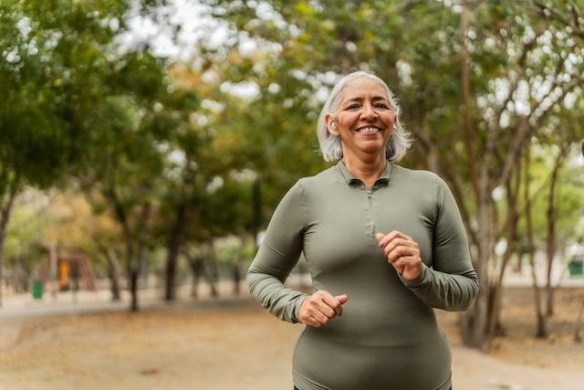 An older woman walks in a park.