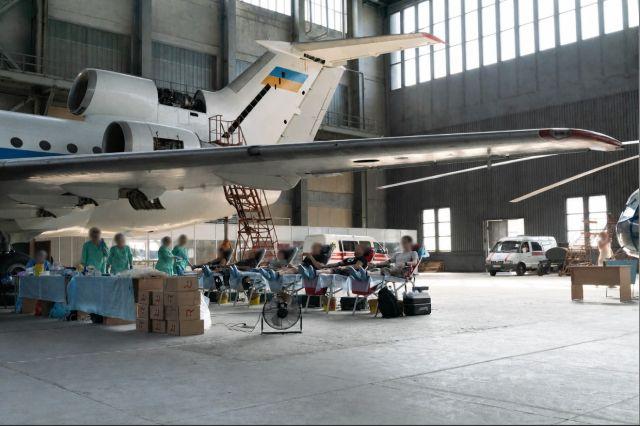 Blood donation in airport hanger in Ukraine during the ongoing war. Faces are blurred to protect identities. 