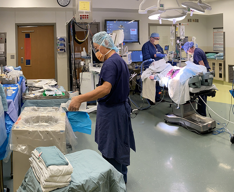 A scrub tech prepares instruments for Kris Anderson'